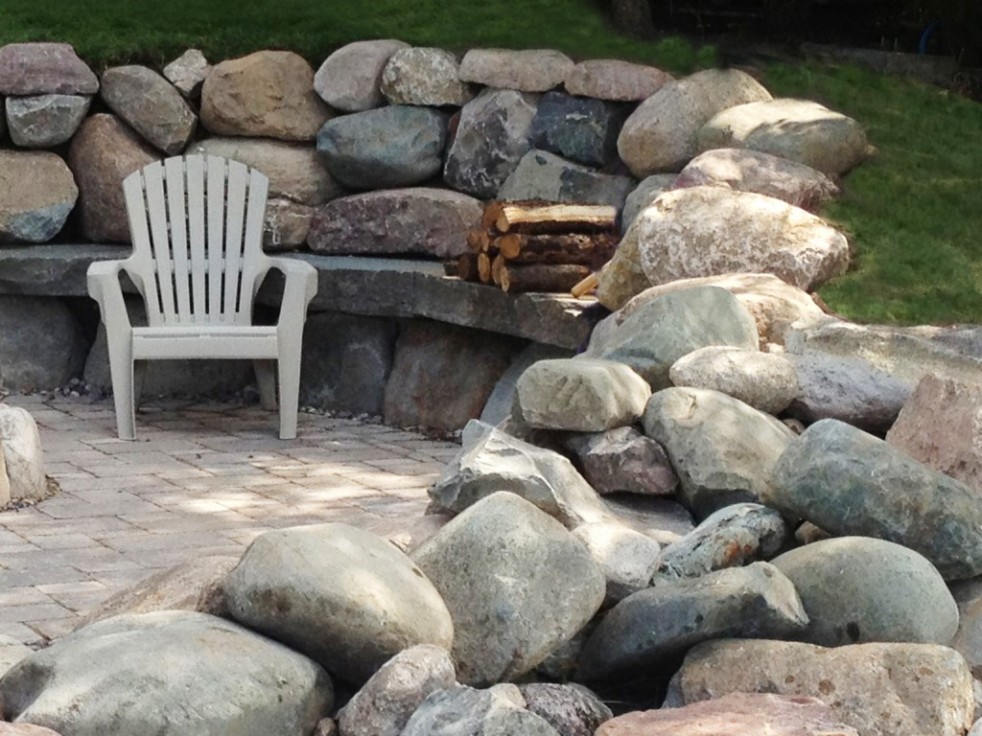 Larg rock wall creating a cozy patio in the backyard